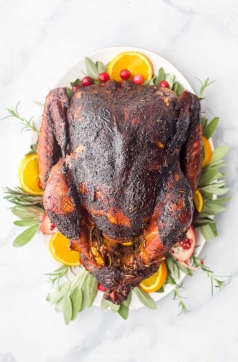 whole maple smoked turkey on a platter with oranges and cranberries