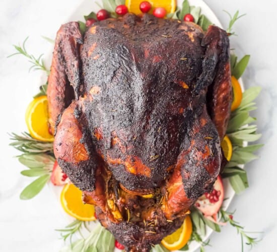 whole maple smoked turkey on a platter with oranges and cranberries