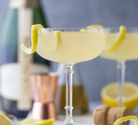 A French 75 cocktail on a kitchen countertop beside a cork and a cocktail measurer