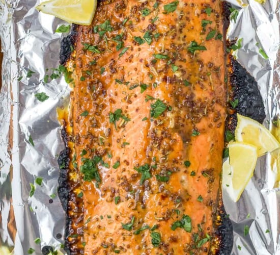 A foil-lined baking sheet with a baked Dijon maple glazed salmon fillet on top of it