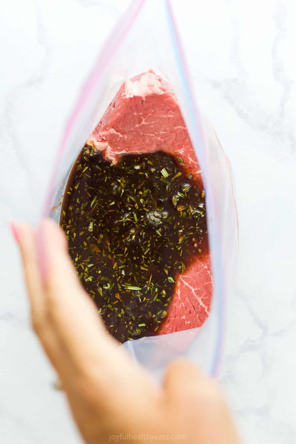 生牛排装在一个大的密封塑料袋里，腌汁浇在上面